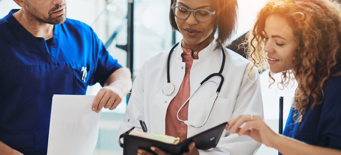 Diverse group of young doctors standing together in a hospital corridor discussing a patient's diagnosis